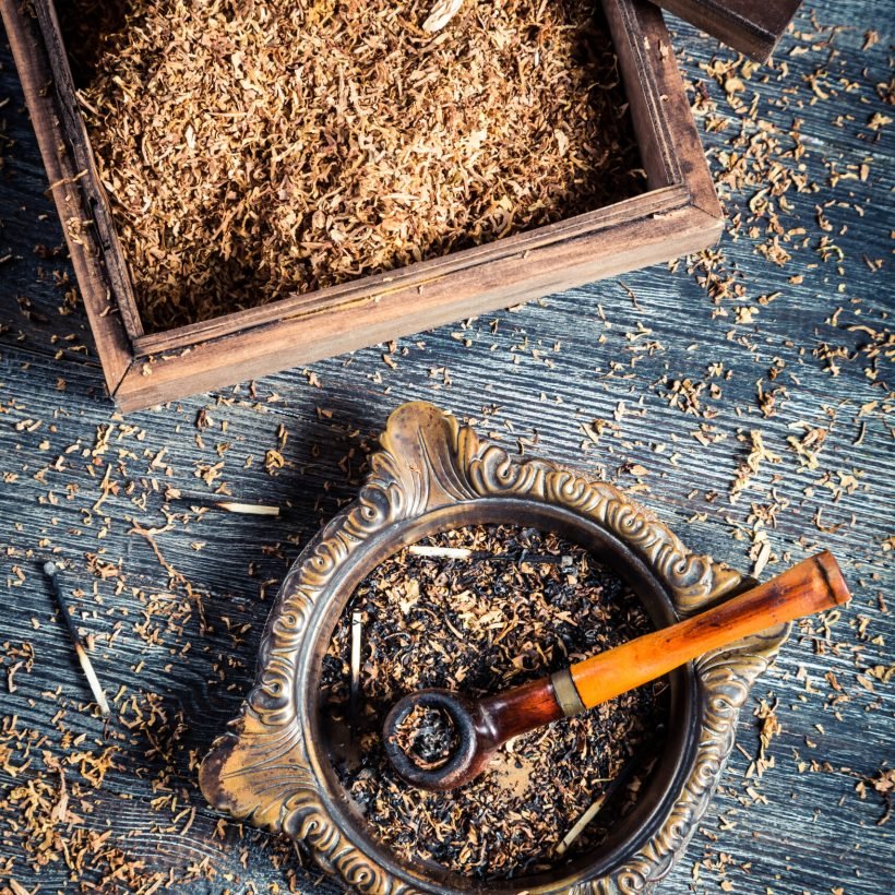 Old wooden pipe with tobacco in an ashtray